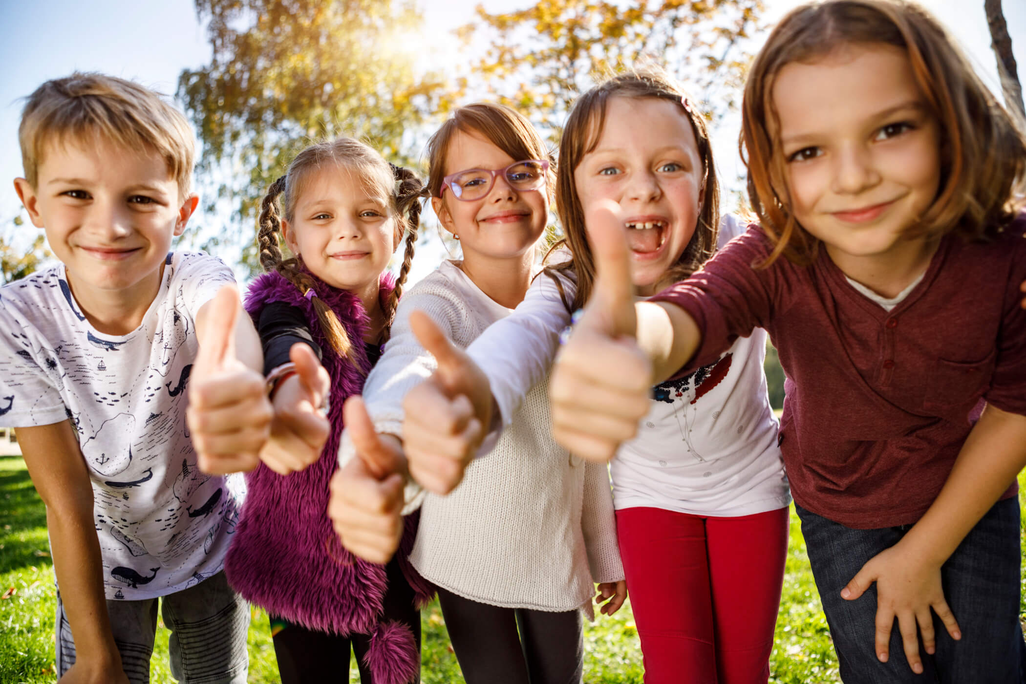 Fröhliche Kinder zeigen Daumen nach oben